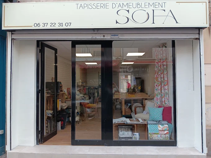 La devanture de SOFA, son enseigne de tapisserie d’ameublement et les tissus présentés en vitrine